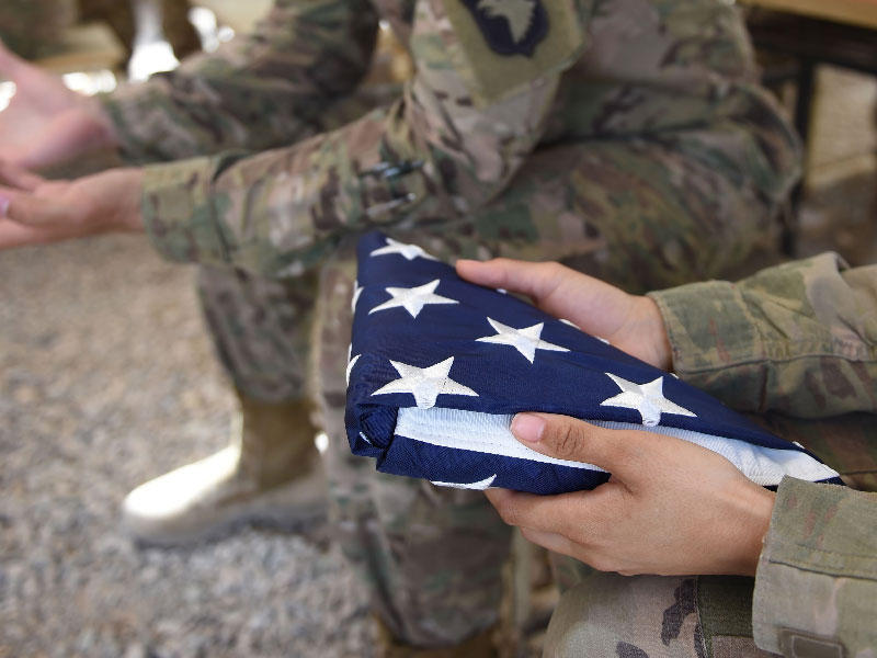 جندي أمريكي يحمل العلم الوطني قبل حفل تسليم في معسكر ليذرنيك في لاشكار جاه في إقليم هلمند الأفغاني