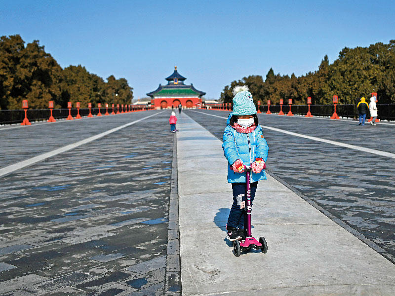 فتاة صينية ترتدي الكمامة تلهو في منتزه يبدو خالياً في بكين أمس (أ ف ب)