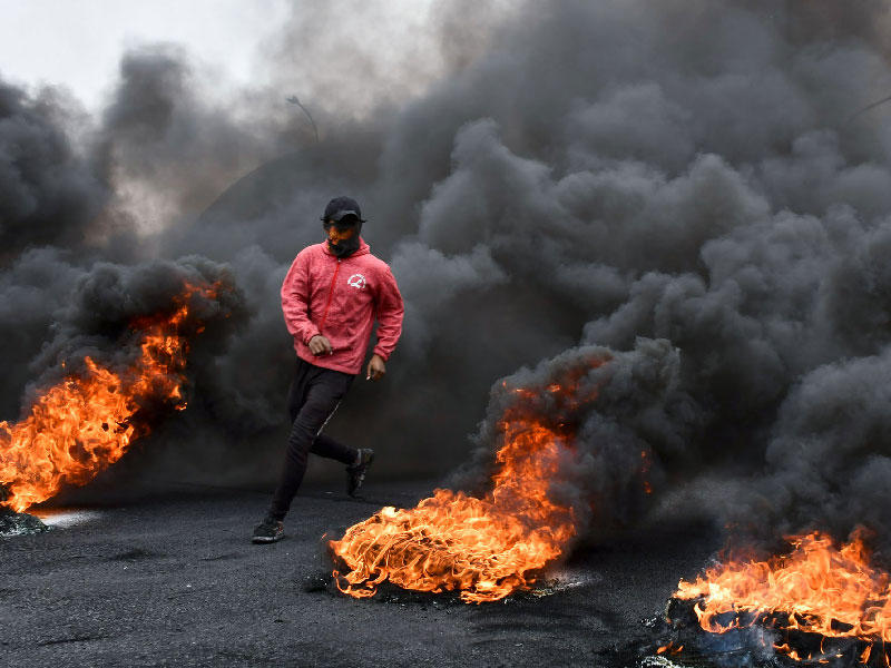 متظاهر عراقي يمر عبر إطارات محترقة