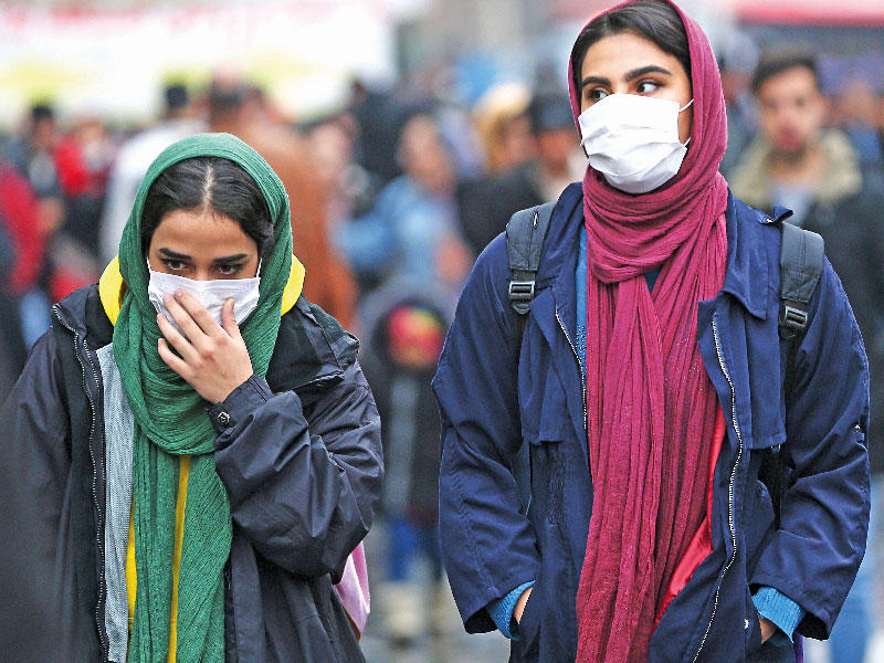 إيرانيتان ترتديان كمامتين في البازار الكبير بطهران أمس (رويترز)