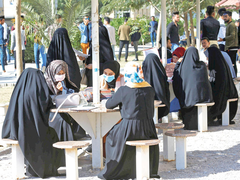 عراقيات يضعن الكمامات الواقية في أحد أسواق النجف أمس   (رويترز)