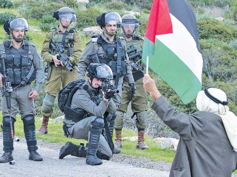 مسن فلسطيني يواجه جنوداً إسرائيليين في غور الأردن بالضفة امس (أ ف ب)