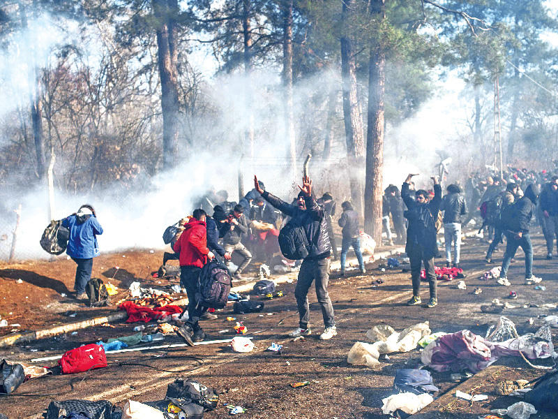 مهاجرون يواجهون الشرطة اليونانية على حدود تركيا أمس (أ ف ب)