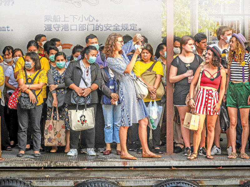 سياح في بانكوك ينتظرون وصول مركب لاصطحابهم برحلة بحرية أمس      (أ ف ب)