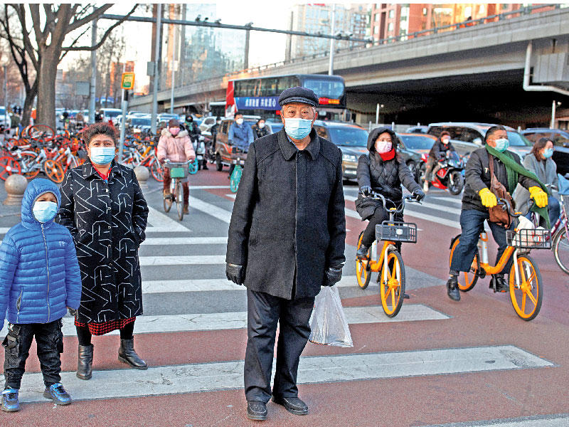 صينيون يضعون الكمامات في بكين أمس (رويترز)