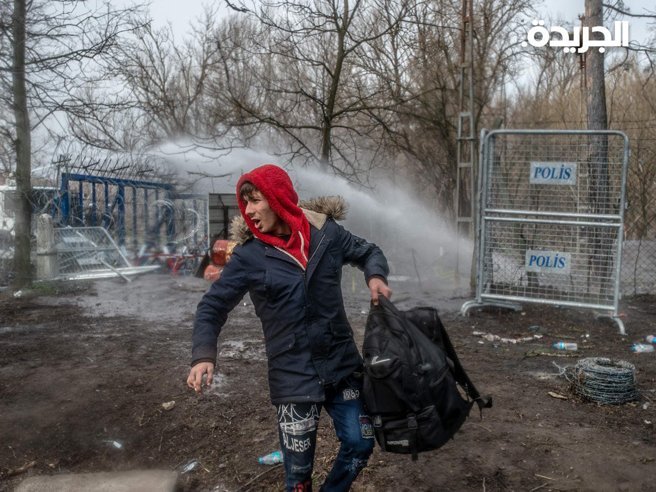 مهاجر يقف أمام ضباط الشرطة اليونانية على الحدود العازلة بين تركيا واليونان