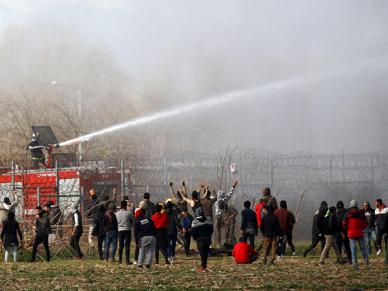 مهاجرون يواجهون قوات مكافحة الشغب اليونانية على حدود تركيا أمس (رويترز)