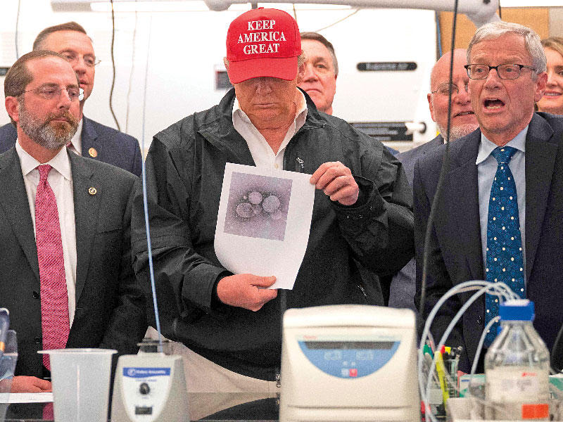 ترامب يحمل صورة لفيروس كورونا خلال زيارته مقرات السيطرة والوقاية من الأمراض  في جورجيا أمس الأول (أ ف ب)