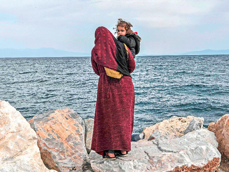 مهاجرة تحمل ابنها قبالة جزيرة ليسبوس اليونانية امس الأول (أ ف ب)