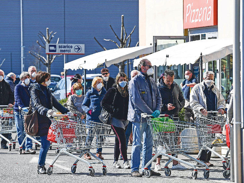 إيطاليون يضعون الأقنعة بانتظار دورهم لدخول أحد السوبرماركات  في ميلانو أمس (ا ف ب) 