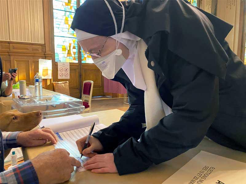 راهبة تضع كماماً وتوقّع بعد ادلائها بصوتها أمس في باريس (ا ف ب)