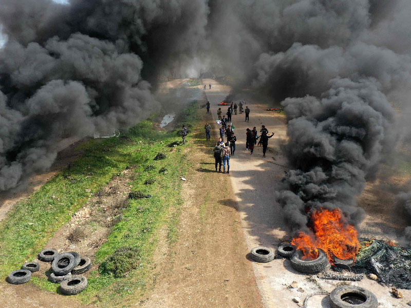 سوريون يحتجون ويحرقون الإطارات في محاولة لمنع حركة المرور على الطريق السريع ، الذي يربط بين محافظات حلب واللاذقية شمال سوريا