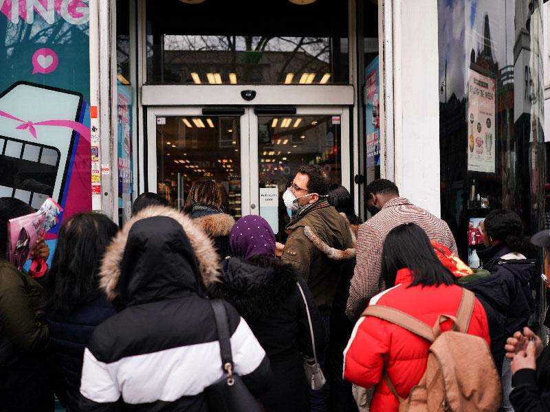 بريطانيون يضعون أقنعة طبية أمام إحدى الصيدليات في لندن أمس (رويترز)