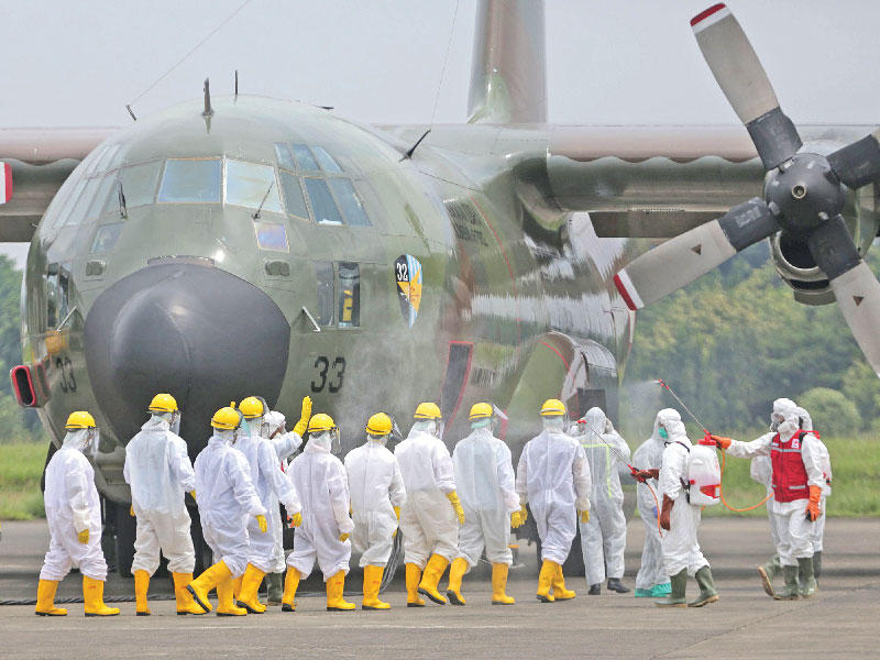 قوة عسكرية إندونيسية تعقّم طائرة محملة بمواد طبية وصلت إلى جاكرتا من الصين أمس  (أ ف ب) 