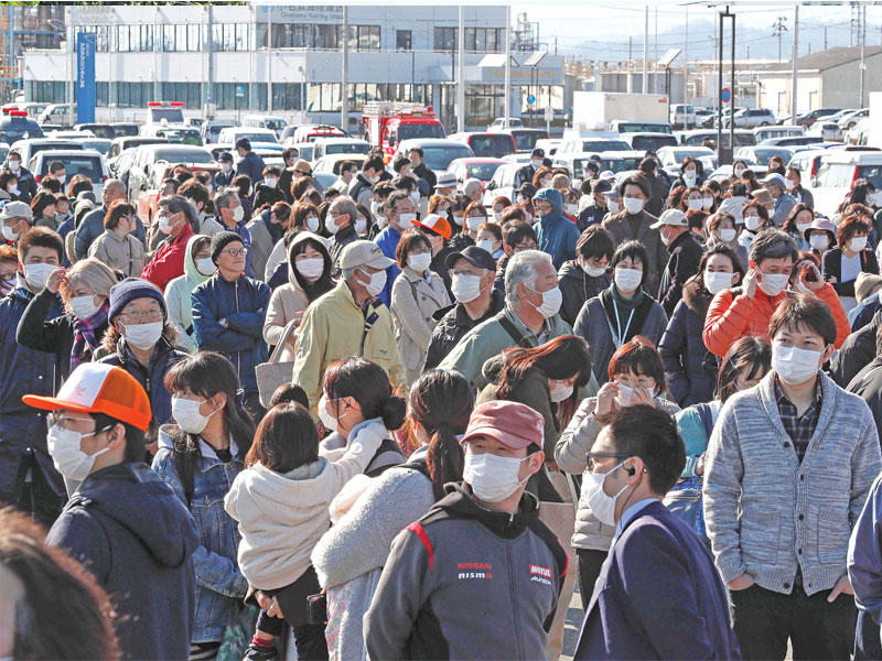 يابانيون يضعون أقنعة واقية يشاهدون الشعلة الأولمبية في مدينة أيواكي فوكوشيما أمس (اي بي ايه)