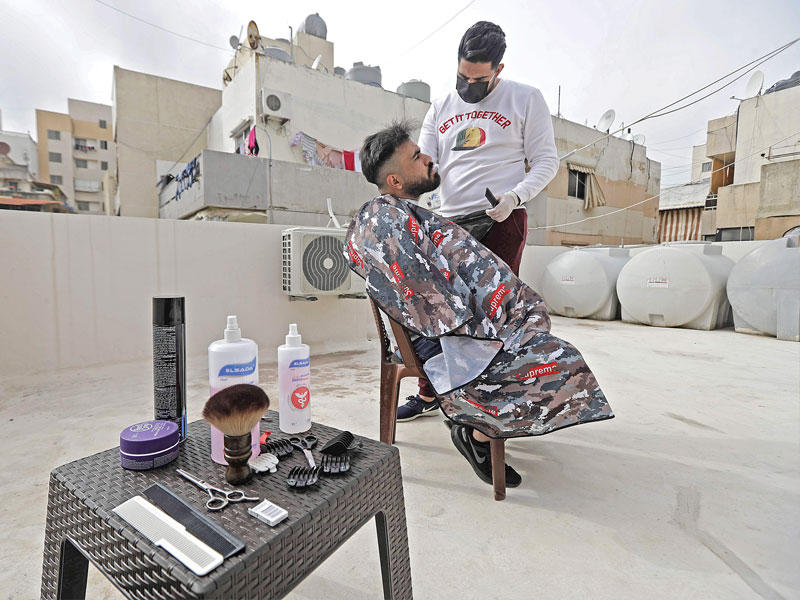 حلاق يقص شعر شاب على سطح عمارة في بيروت (أ ف ب)