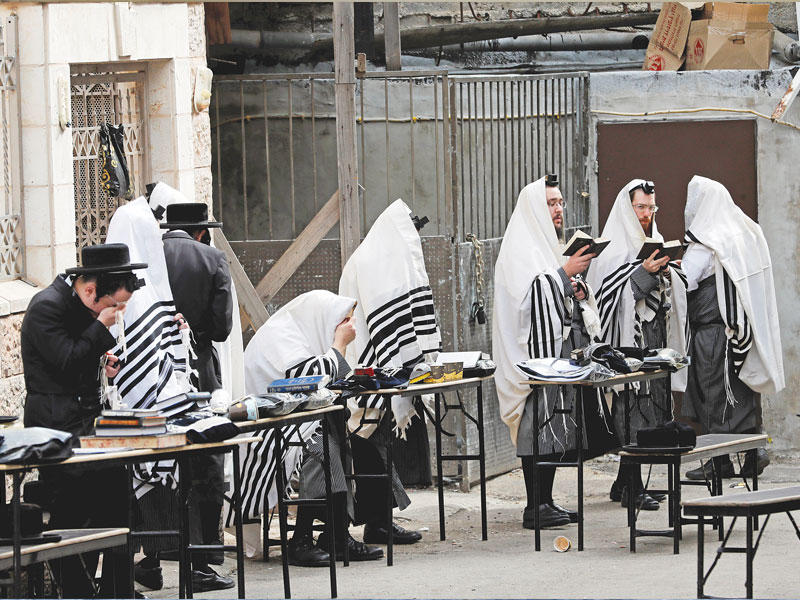 يهود يؤدون صلواتهم خارج كنيس بالقدس المحتلة   (رويترز)