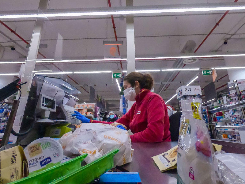 بائعة  ترتدي أقنعة الوجه في السوبر ماركت في منطقة بورتوينس في روما