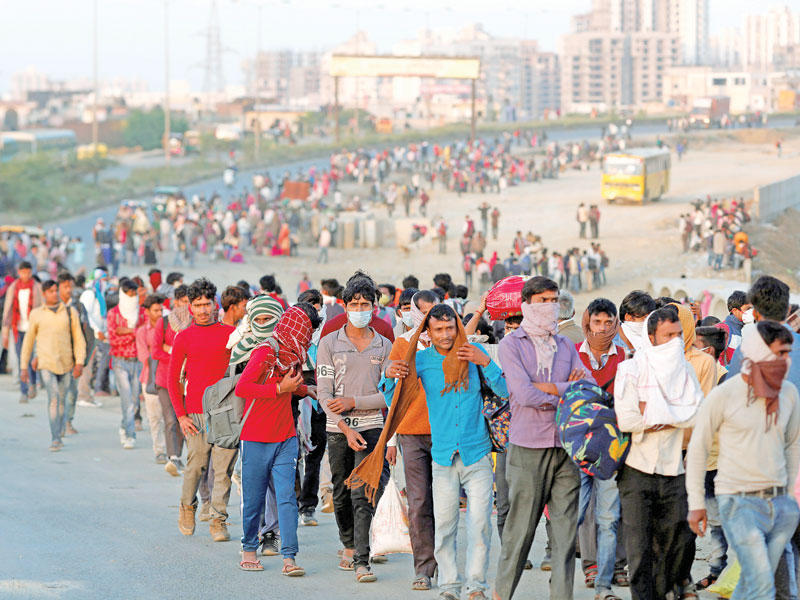 آلاف العاملين الهنود مع عائلاتهم في طريقهم إلى محطة الحافلات في ضاحية غازي آباد بنيودلهي قبل العودة إلى قراهم أمس (رويترز)