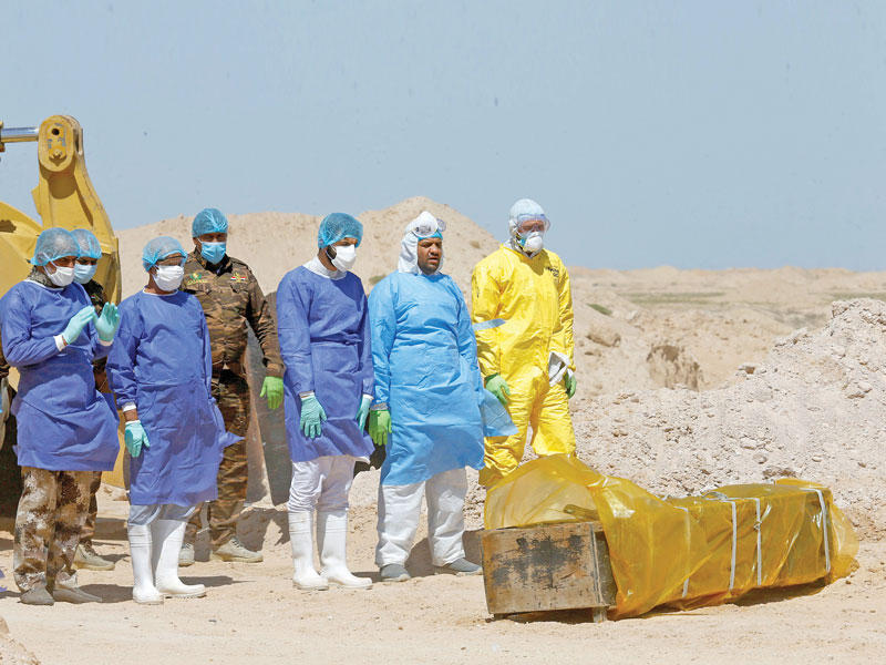 عناصر من الحشد الشعبي يشيعون مع فريق طبي عراقياً توفي بفيروس كورونا (رويترز)