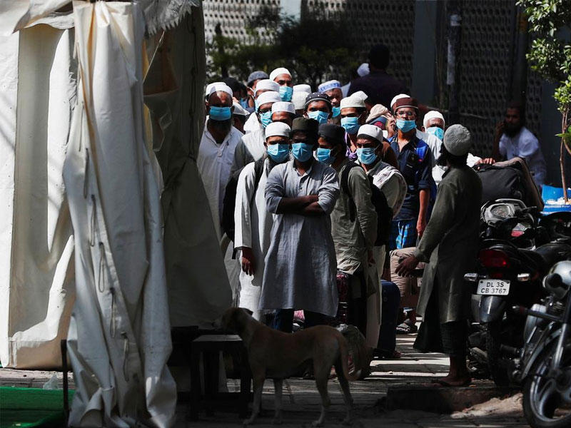 أفراد يضعون كمامات واقية بانتظار حافلة لنقلهم إلى الحجر الصحي في نيودلهي n