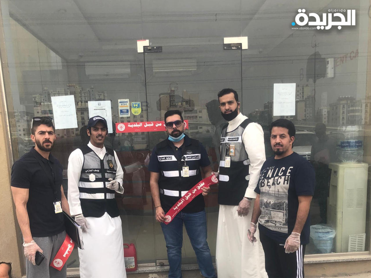 موظفو البلدية يضعون ملصق إغلاق على احد المحلات المخالفة