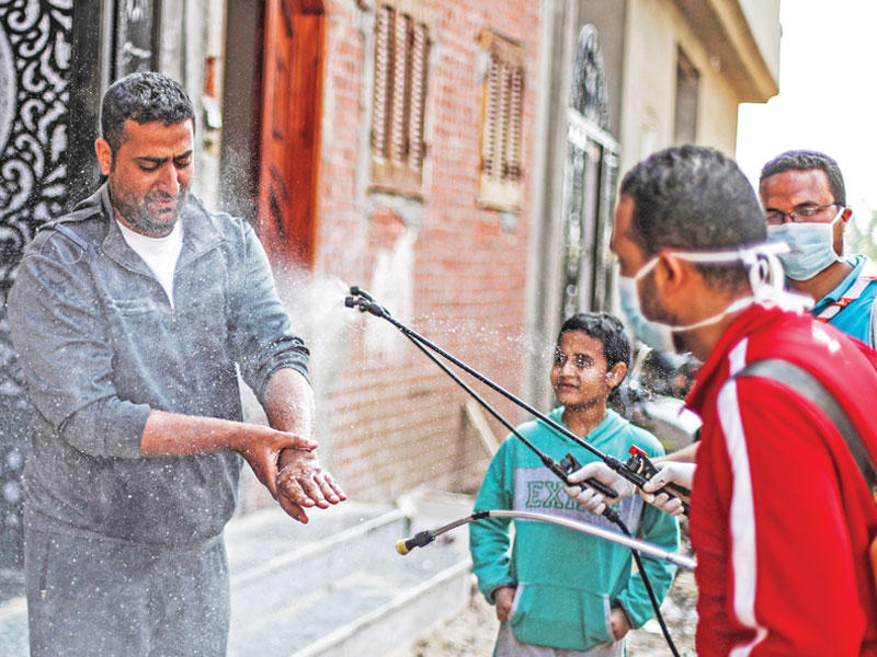 مصري يعقّم أحد الأشخاص في قرية الشما (ا ف ب)