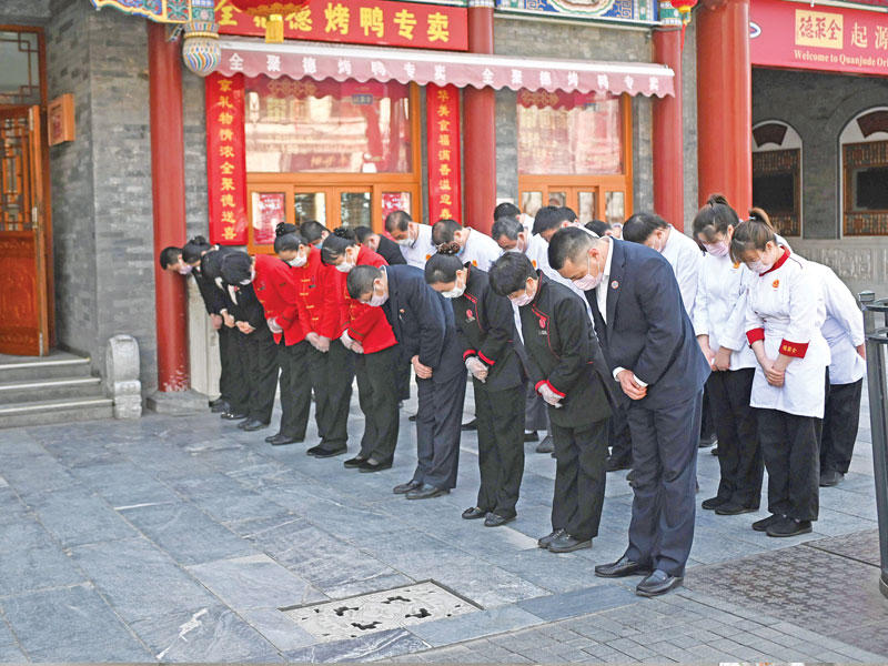 صينيون يقفون دقيقة صمت حداداً على أرواح ضحايا «كورونا» في بكين أمس (أ ف ب)
