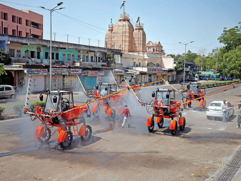 آليات تابعة للدفاع المدني الهندي خلال تعقيم إحدى المناطق في أحمد آباد أمس (رويترز)