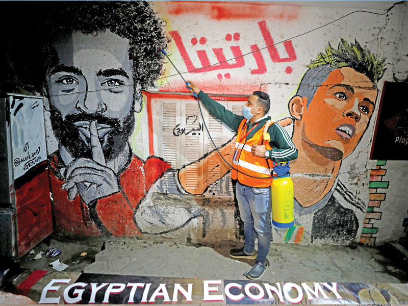 متطوّع مصري يشارك في تعقيم أحد الأحياء في منطقة شبرا الخيمة أمس الأول (رويترز) 