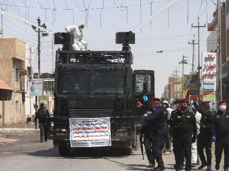 أفراد من شرطة مكافحة الشغب يرتدون أقنعة وقفازات واقية للوجه يرشون الماء المعقم في الشوارع والأسواق . العراق