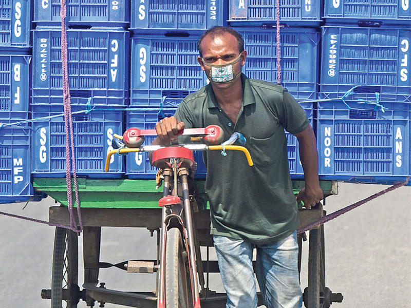 عامل من بنغلادش يجر شعارات الصناديق على دراجة هوائية في دكا أمس t(أ ف ب)