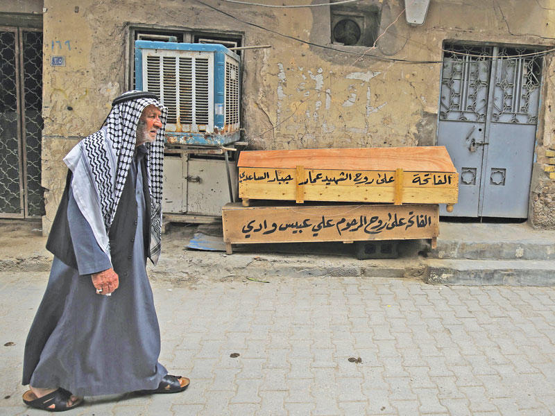 عراقي يمر أمام توابيت فارغة في حي الوشاش غرب بغداد أمس الأولt (أ ف ب)