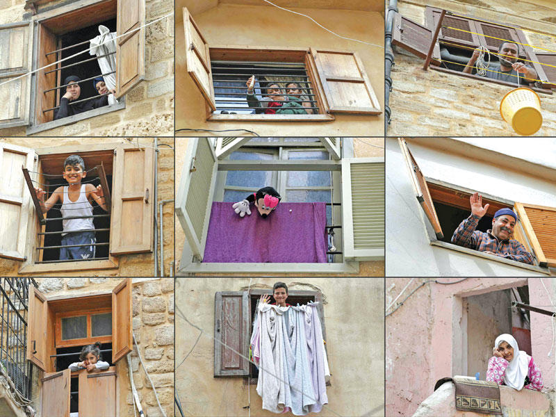 لبنانيون على النوافذ والشرفات في ظل العزل  (أ ف ب)