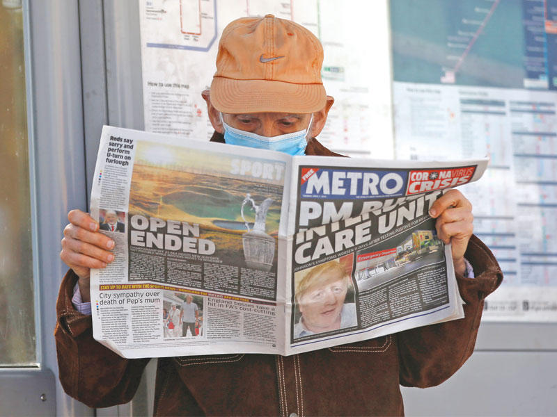 بريطاني يطالع صحيفة تحمل صورة كبيرة لجونسون على صفحتها الأولى أمس  (رويترز)