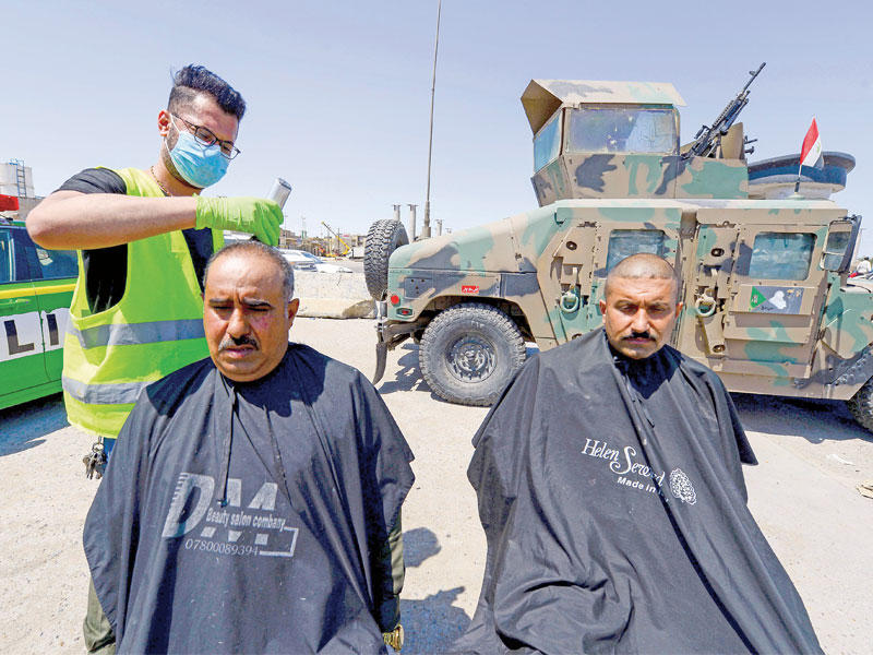 حلاقة بالهواء الطلق لعناصر الأمن في النجف (أ ف ب) 