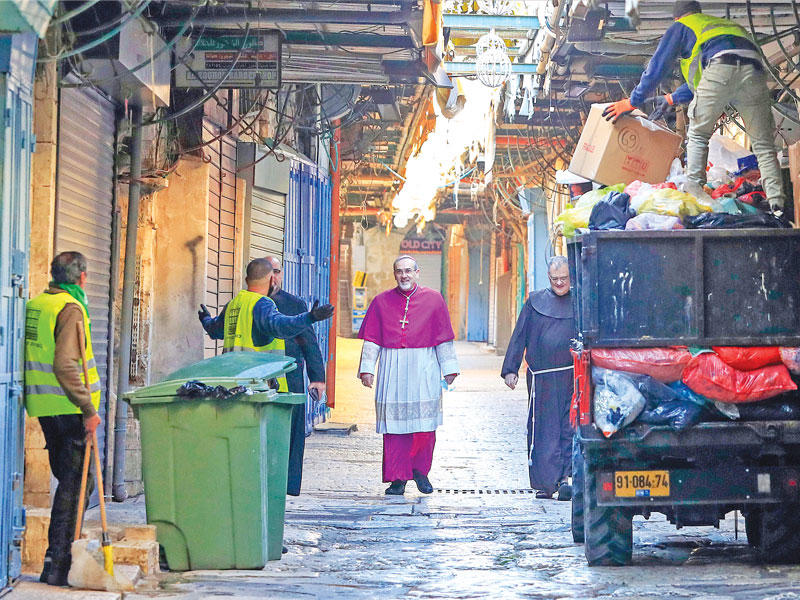 عمال نظافة يرحّبون برجل دين مسيحي في شوارع القدس القديمة الخالية أمس (ا ف ب)