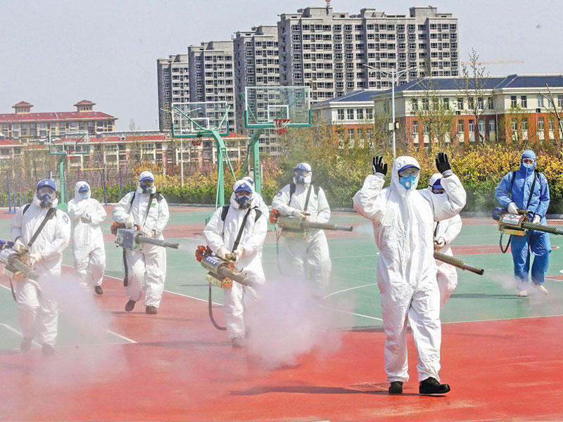 متطوّعون صينيون يرشّون معقّمات في إحدى باحات مدارس مقاطعة شاندونغ  استعداداً لإعادة فتحها قريباً        (أ ف ب)