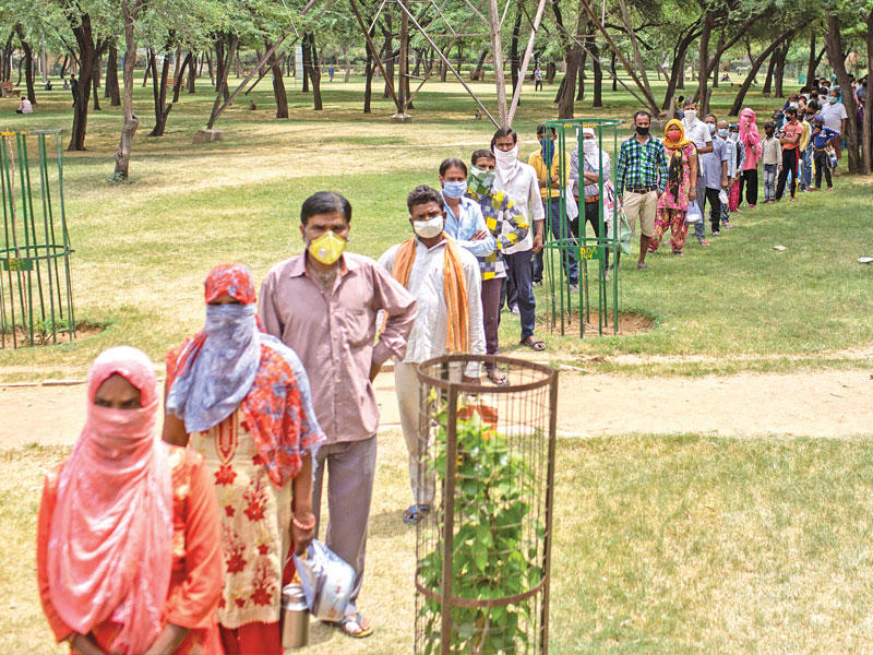 هنود ينتظرون في طابور للحصول على وجبة طعام مجانية في نيودلهي أمس (رويترز)