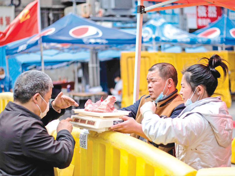 احد الاشخاص في الصين يشتري احتياجاته من خلف حاجز في مدينة ووهان الصينية