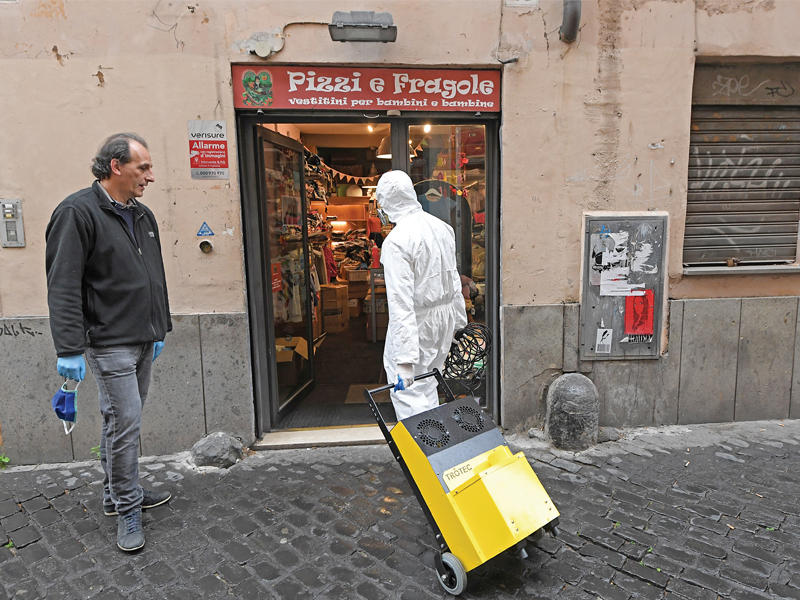 عامل بثياب واقية يدخل متجراً مخصصاً للأطفال بروما أمس، مع تخفيف الحكومة الإيطالية قيود «كورونا» (رويترز)