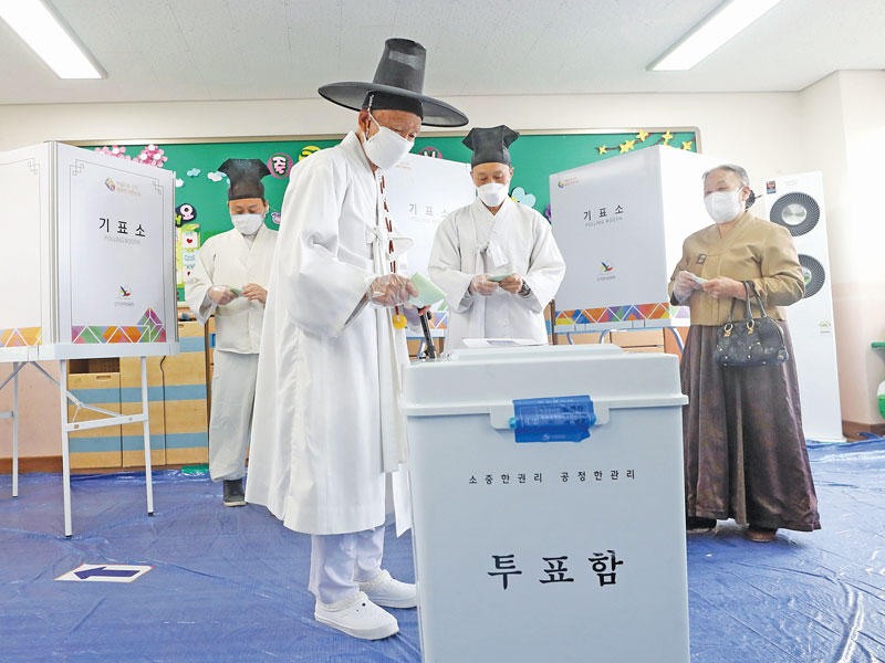 المعلم كونفوشي يو بوك يوب وعائلته يقترعون في نونسان أمس وهم يرتدون ثياباً تقليدية واقنعة الوقاية من «كورونا»  (أ ف ب)