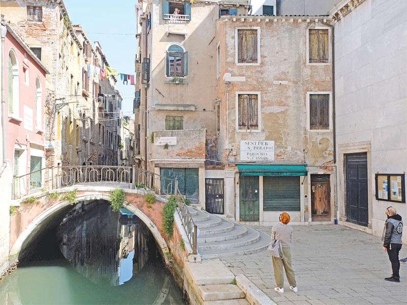 ايطالي وزوجته يتحدثان مع جارتهما في منزلها بالبندقية أمس الأول (رويترز)