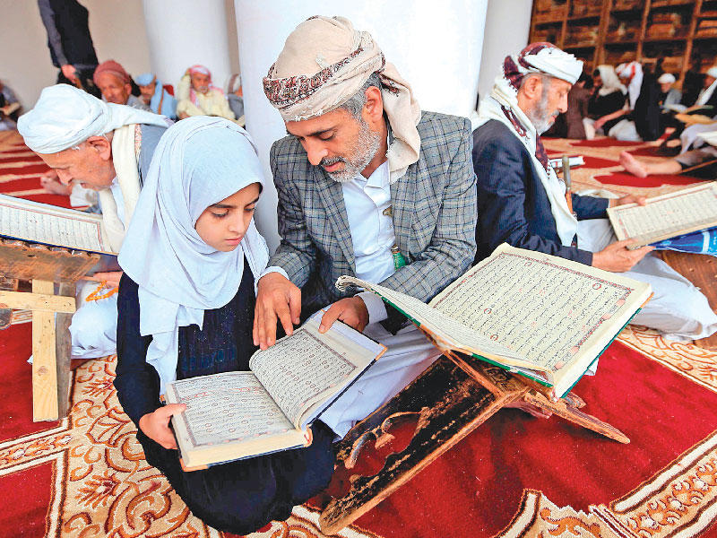 يمني وابنته يتلوان القرآن في المسجد الكبير بصنعاء أمس الأول   (أ ف ب)