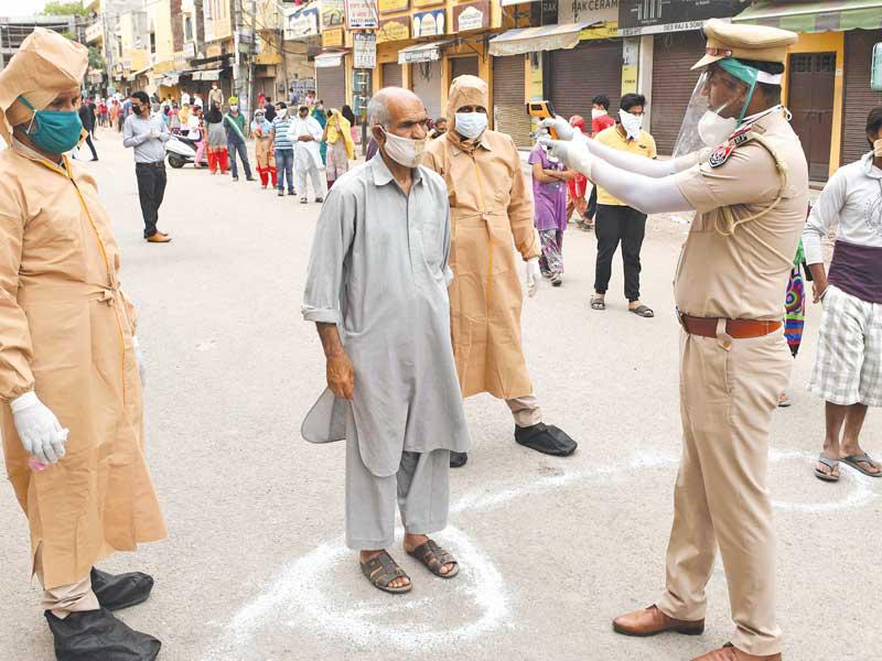 شرطي هندي يتحقّق من حرارة أحد مواطنيه في مدينة أمريستار أمس       (أ ف ب)