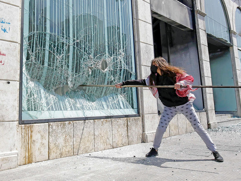 متظاهرة تحطم واجهة مصرف في طرابلس أمسt(أ ف ب)