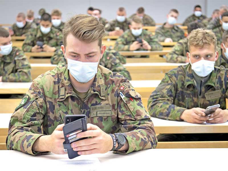 جنود سويسريون يتدرّبون على استخدام هواتفهم في كيفية تحديد الأشخاص المخالطين لمصابين بالفيروس أمس (اي بي ايه)