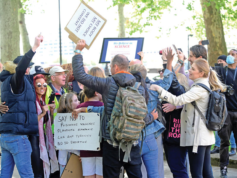 معارضون لإجراءات الحجر والعزل، وبينهم اطفال، يتحدون قواعد التباعد الاجتماعي في لندن أمام مقر سكوتلانديارد أمس (رويترز) 