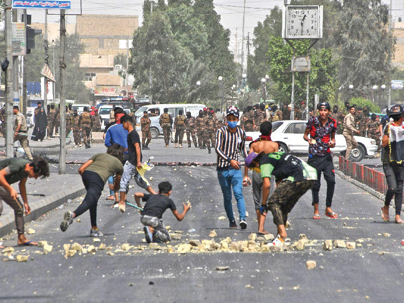 عراقيون يواجهون قوات الأمن بالحجارة في الناصرية أمس (أ ف ب)