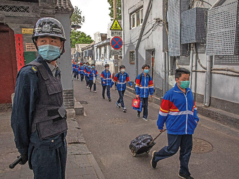 طلاب صينيون في بكين أمس مع عودة المدارس جزئياً إلى فتح أبوابها      (إي بي أيه)